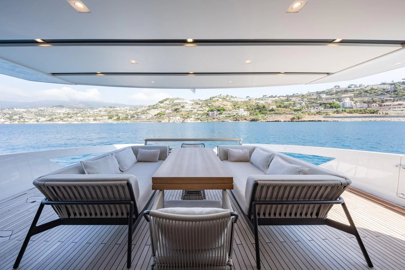 The aft deck features a stylish and comfortable seating area with a dining table, perfect for enjoying meals with a view of the water. aboard JUNIOR Yacht for Sale