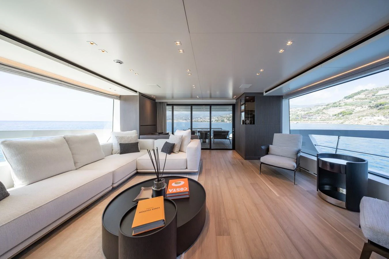 The salon features expansive windows, modern furnishings, and a serene ambiance with a view of the sea. aboard JUNIOR Yacht for Sale