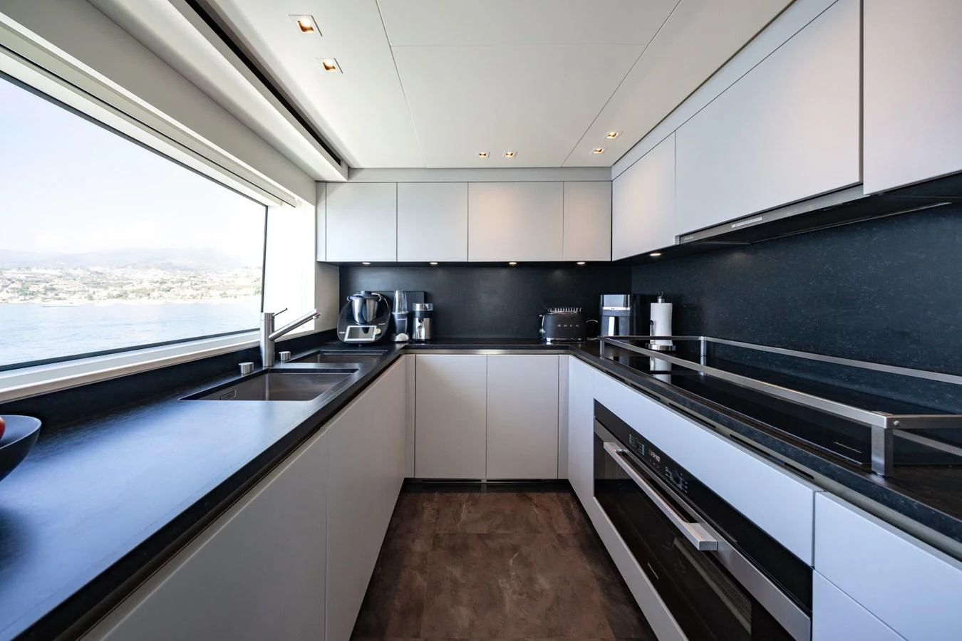 The modern galley features sleek cabinetry, high-end appliances, and a large window with a stunning view. aboard JUNIOR Yacht for Sale