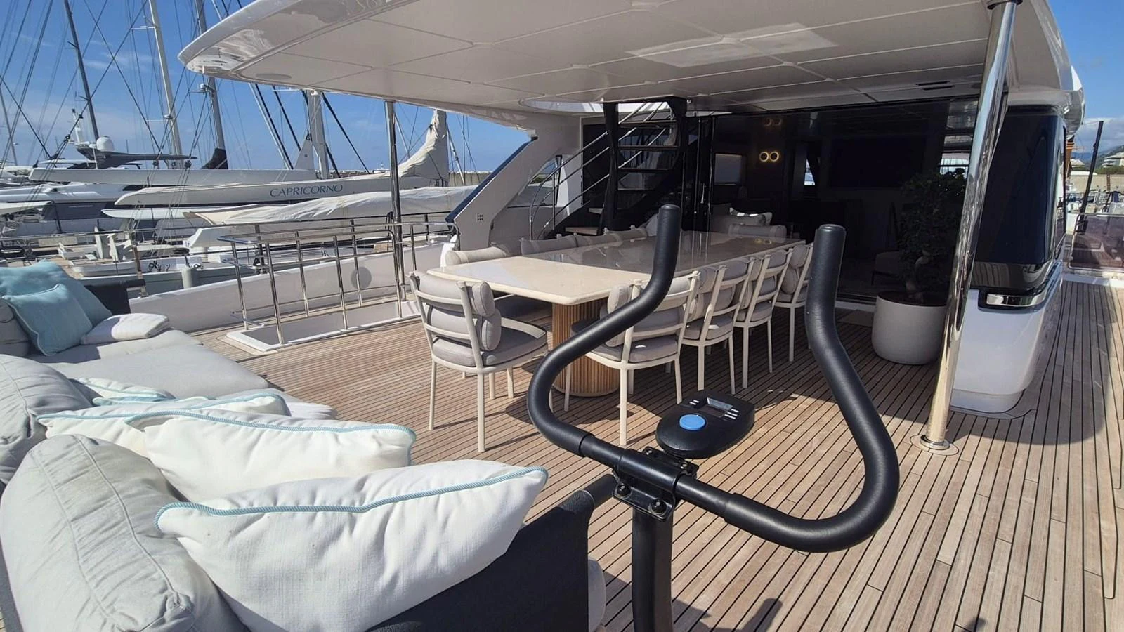 The aft deck features a spacious seating area, dining table, and exercise bike, perfect for relaxation and fitness. aboard SOLE Yacht for Sale