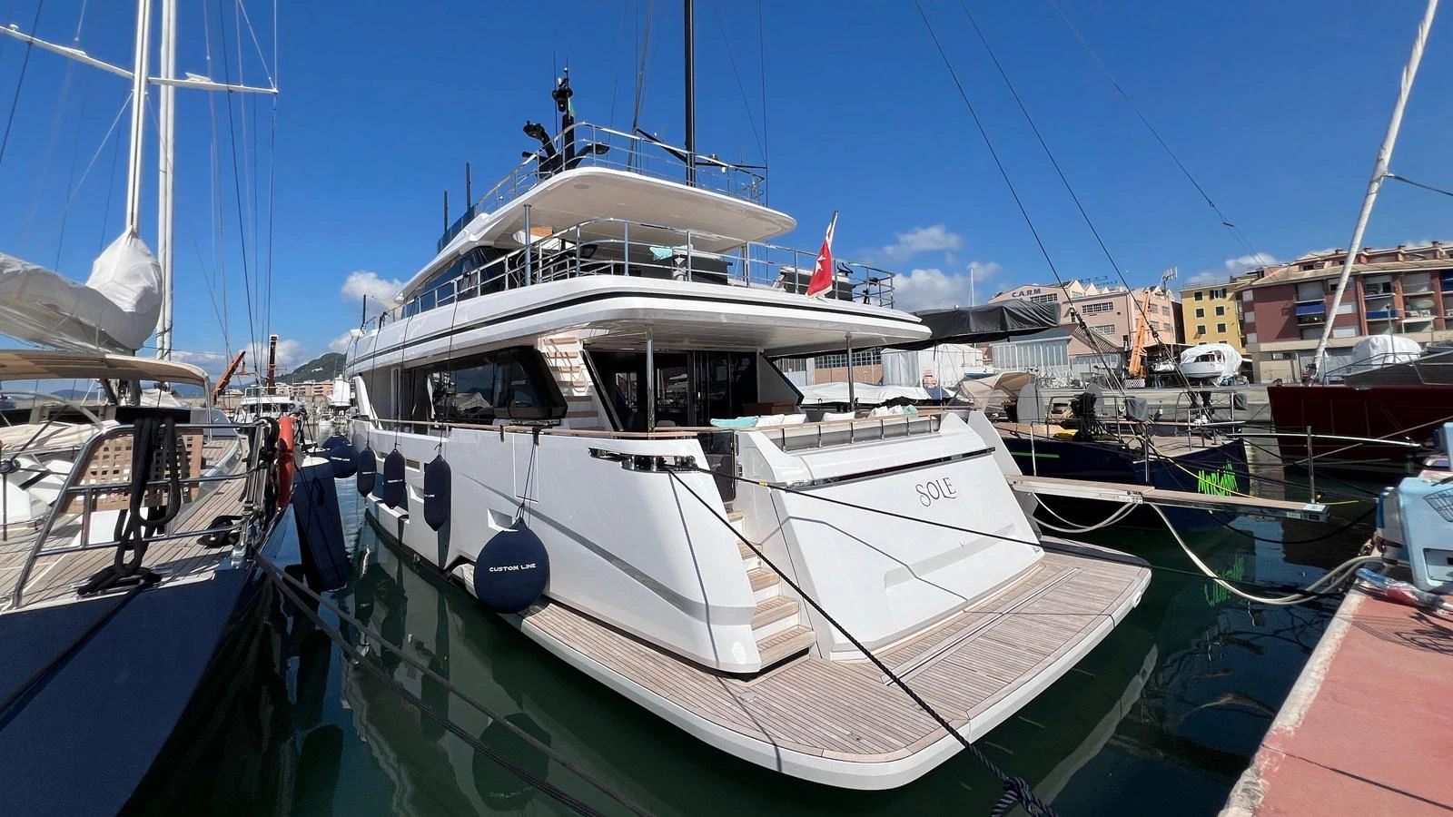 A luxurious yacht docked at a marina under a clear blue sky. aboard SOLE Yacht for Sale