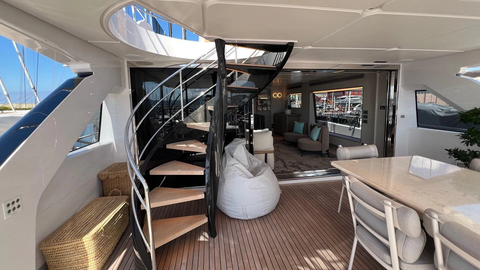 The aft deck features a stylish spiral staircase, comfortable seating, and a dining area with a view of the marina. aboard SOLE Yacht for Sale