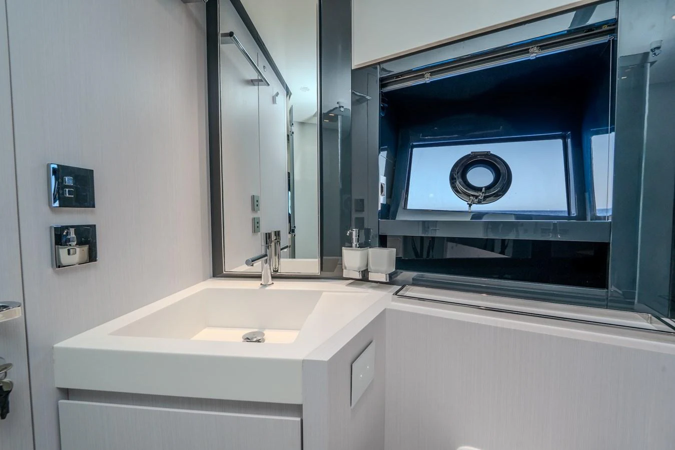 A modern yacht bathroom with sleek fixtures and a porthole window. aboard LUCE I Yacht for Sale