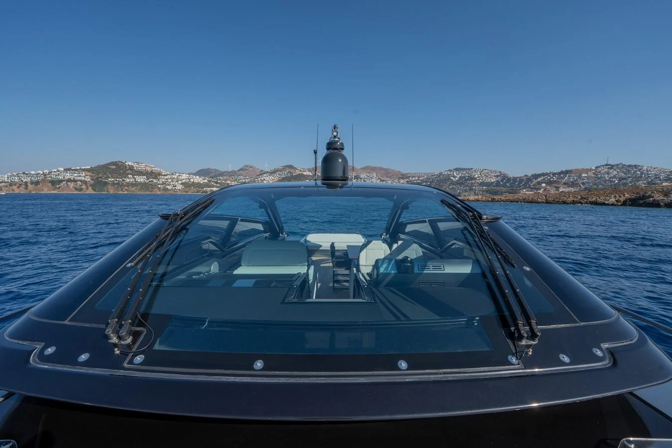 The yacht is captured from the stern, showcasing its sleek design and expansive windows against a scenic coastal backdrop. aboard LUCE I Yacht for Sale