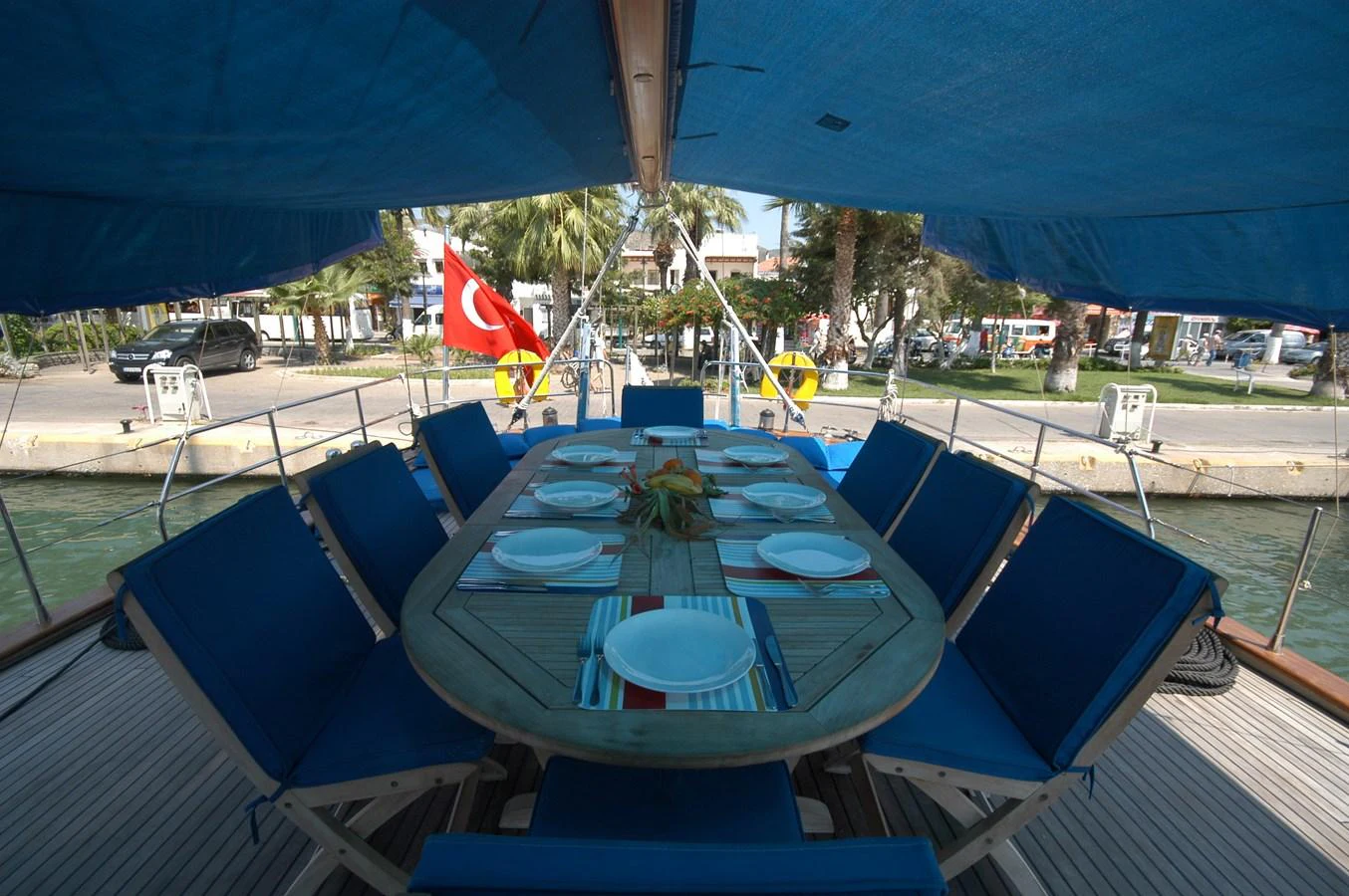 The yacht features an inviting outdoor dining area with a large table set for a meal, shaded by a canopy. aboard ARINNA Yacht for Sale