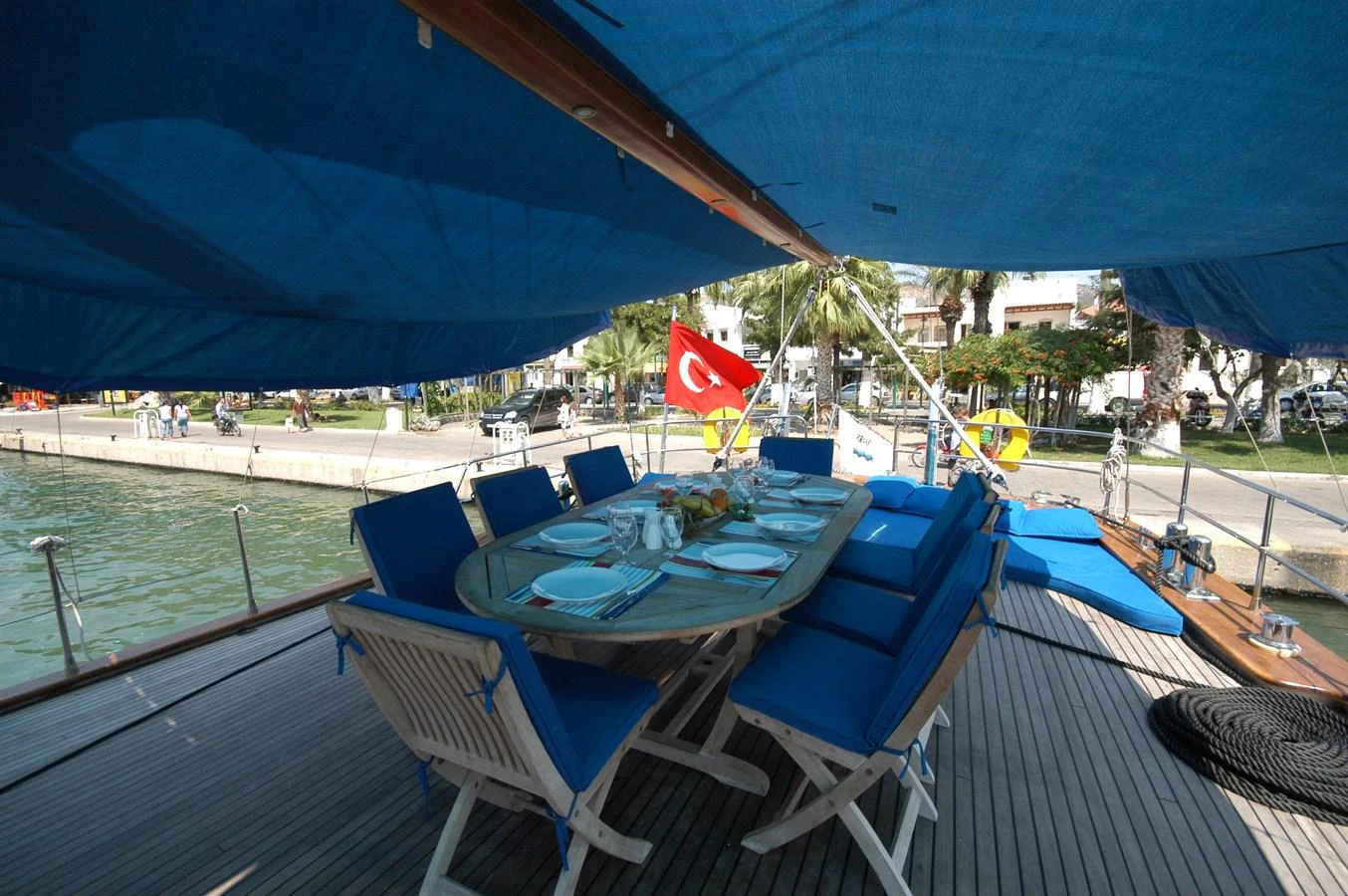 The aft deck features a spacious dining area under a blue canopy, perfect for outdoor meals. aboard ARINNA Yacht for Sale