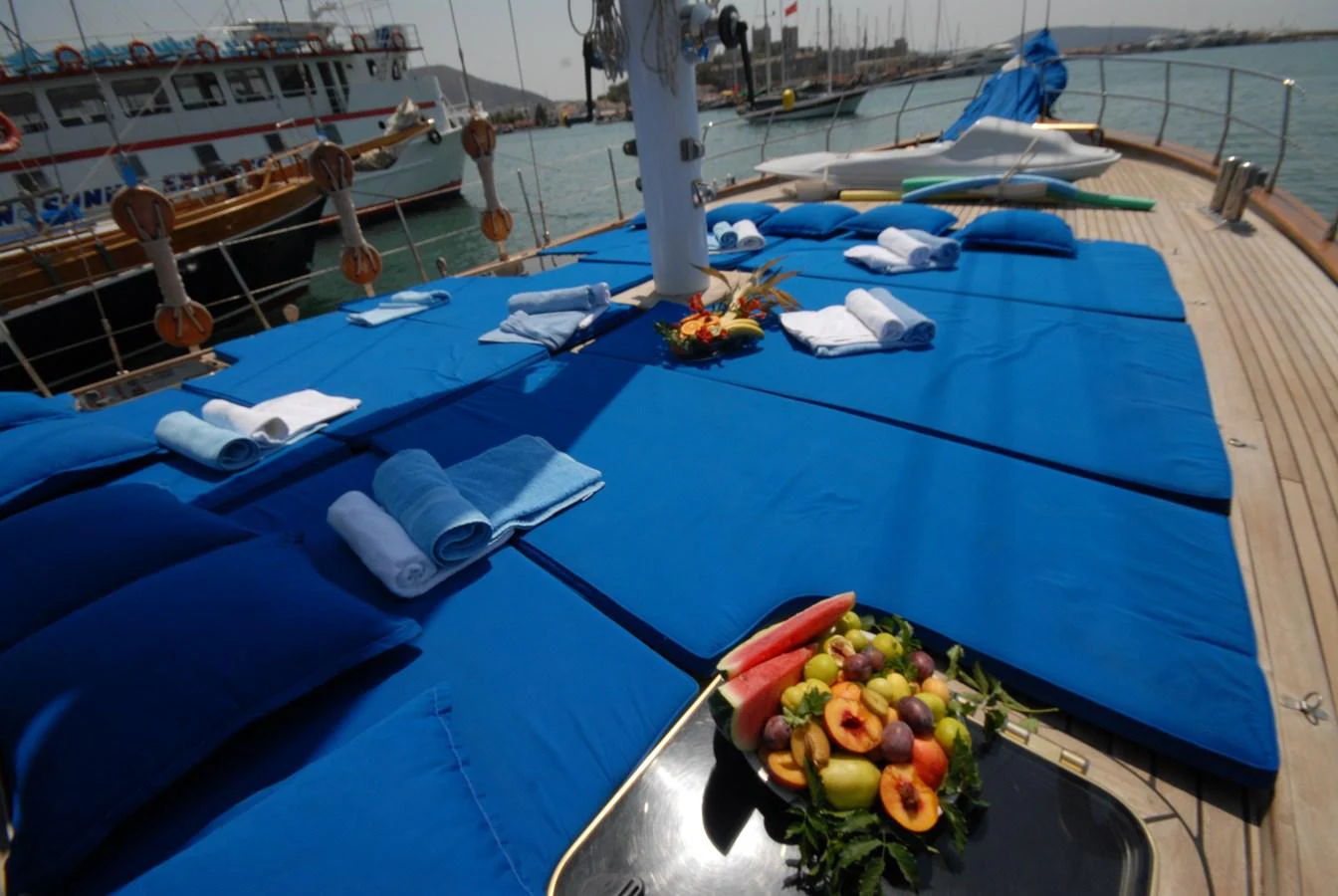 The sundeck features comfortable blue sun pads and a fresh fruit platter, perfect for relaxation. aboard ARINNA Yacht for Sale