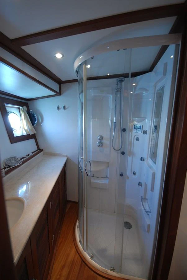 The yacht's bathroom features a modern shower cabin and elegant wooden cabinetry. aboard ARINNA Yacht for Sale