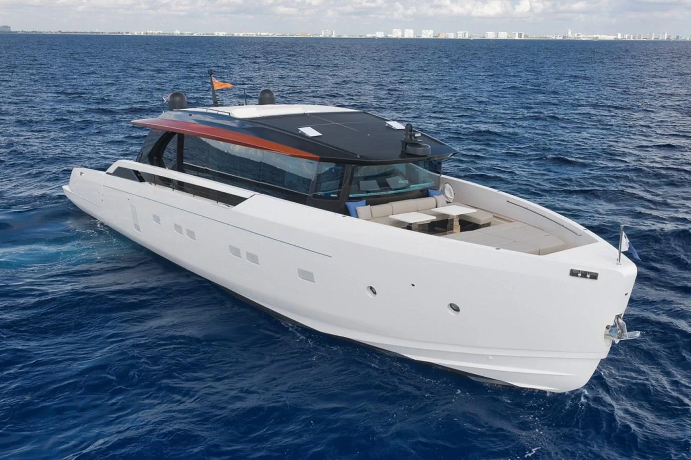 A sleek and modern yacht cruising on the open sea with a cityscape in the background. aboard LAUREN MARIE Yacht for Sale