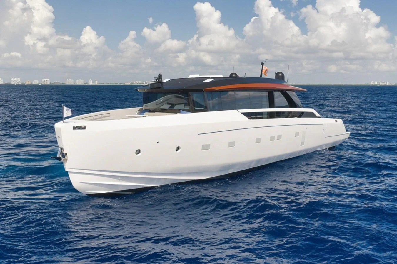 A sleek and modern yacht glides through the vibrant blue waters under a partly cloudy sky. aboard LAUREN MARIE Yacht for Sale