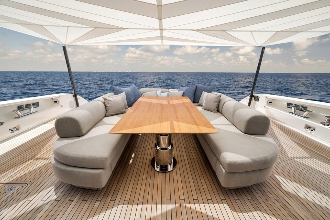 The aft deck features a stylish dining area with plush seating and a wooden table under a shaded canopy. aboard LAUREN MARIE Yacht for Sale