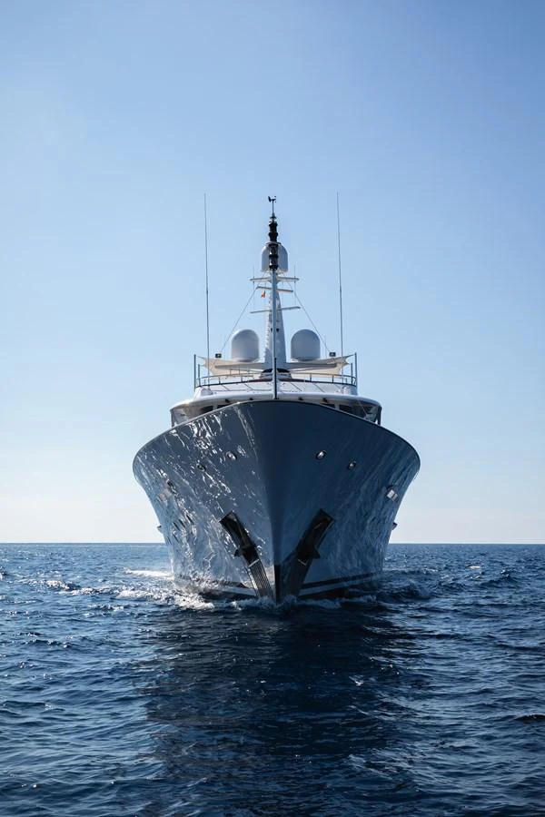 A majestic yacht cruises forward on the open sea under a clear blue sky. aboard MIRAGE Yacht for Sale