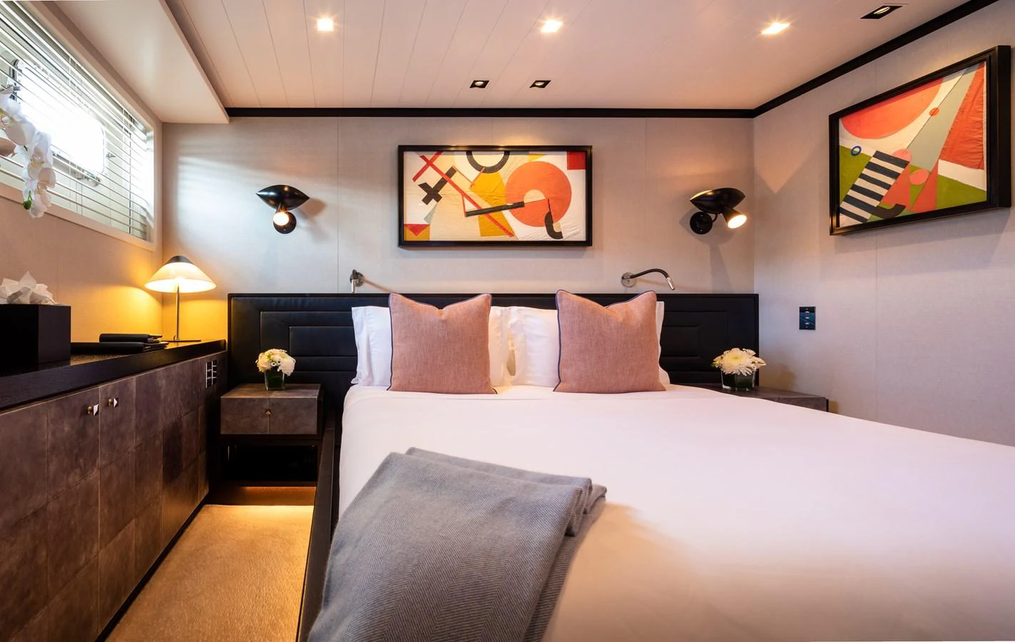 A cozy stateroom featuring a comfortable bed with modern art on the walls. aboard MIRAGE Yacht for Sale