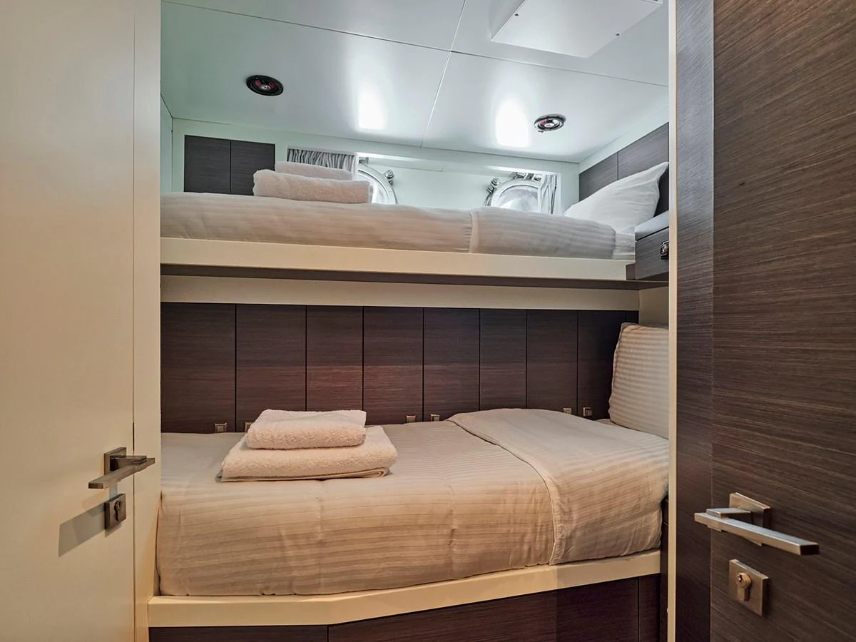 The guest cabin features cozy bunk beds with neatly arranged linens and modern wood paneling. aboard BELITA Yacht for Sale