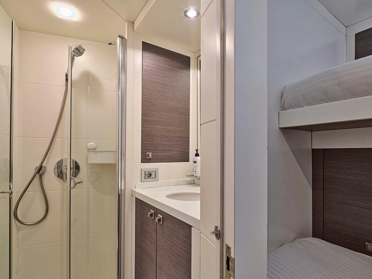 This image showcases a compact and modern yacht bathroom with a shower and adjacent bunk bed area. aboard BELITA Yacht for Sale