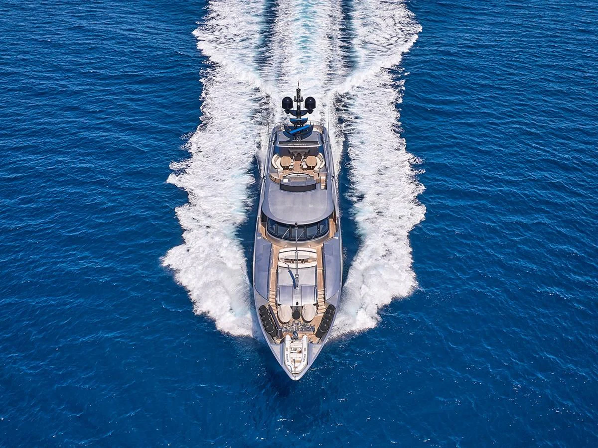 A sleek yacht cruises through vibrant blue waters, leaving a dynamic wake behind. aboard BELITA Yacht for Sale