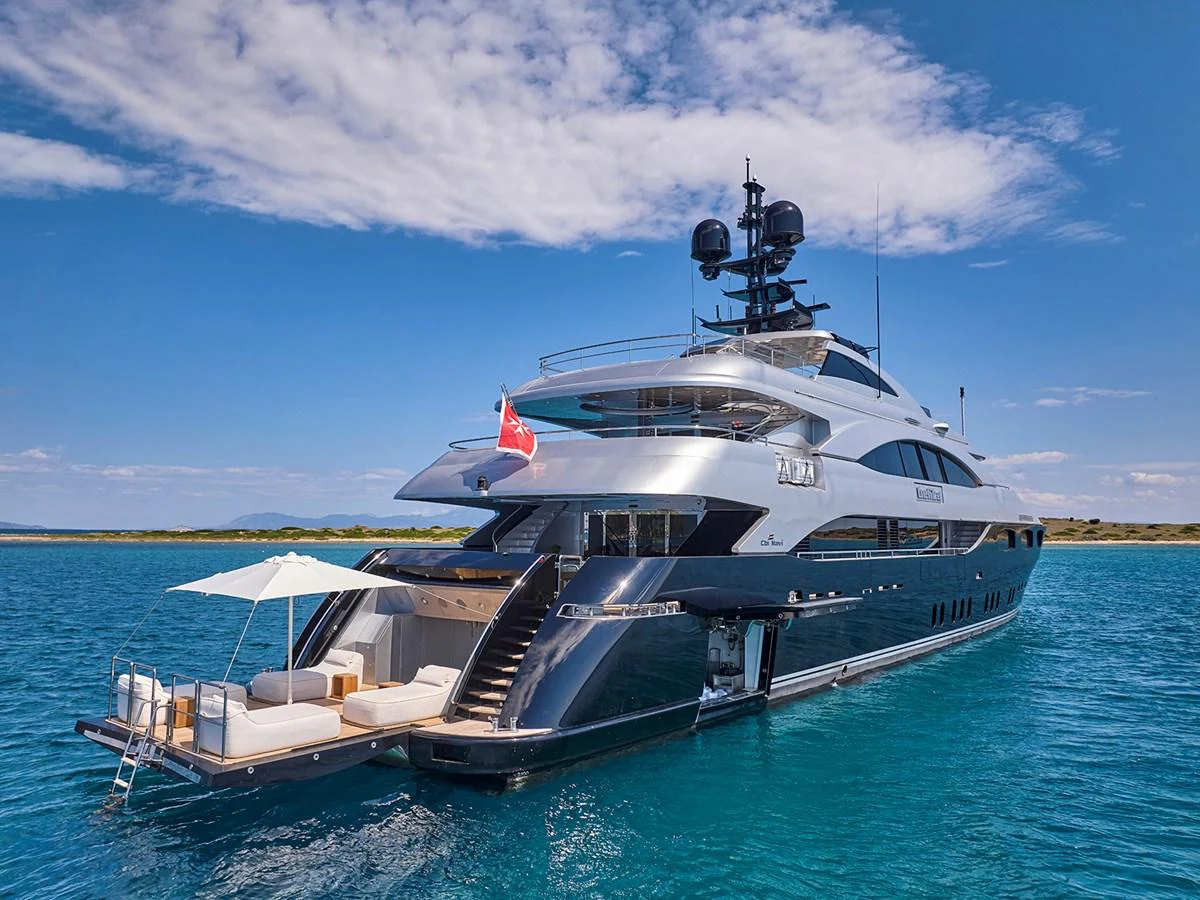 A sleek and modern yacht is anchored in clear blue waters, showcasing its luxurious design and spacious deck area. aboard BELITA Yacht for Sale