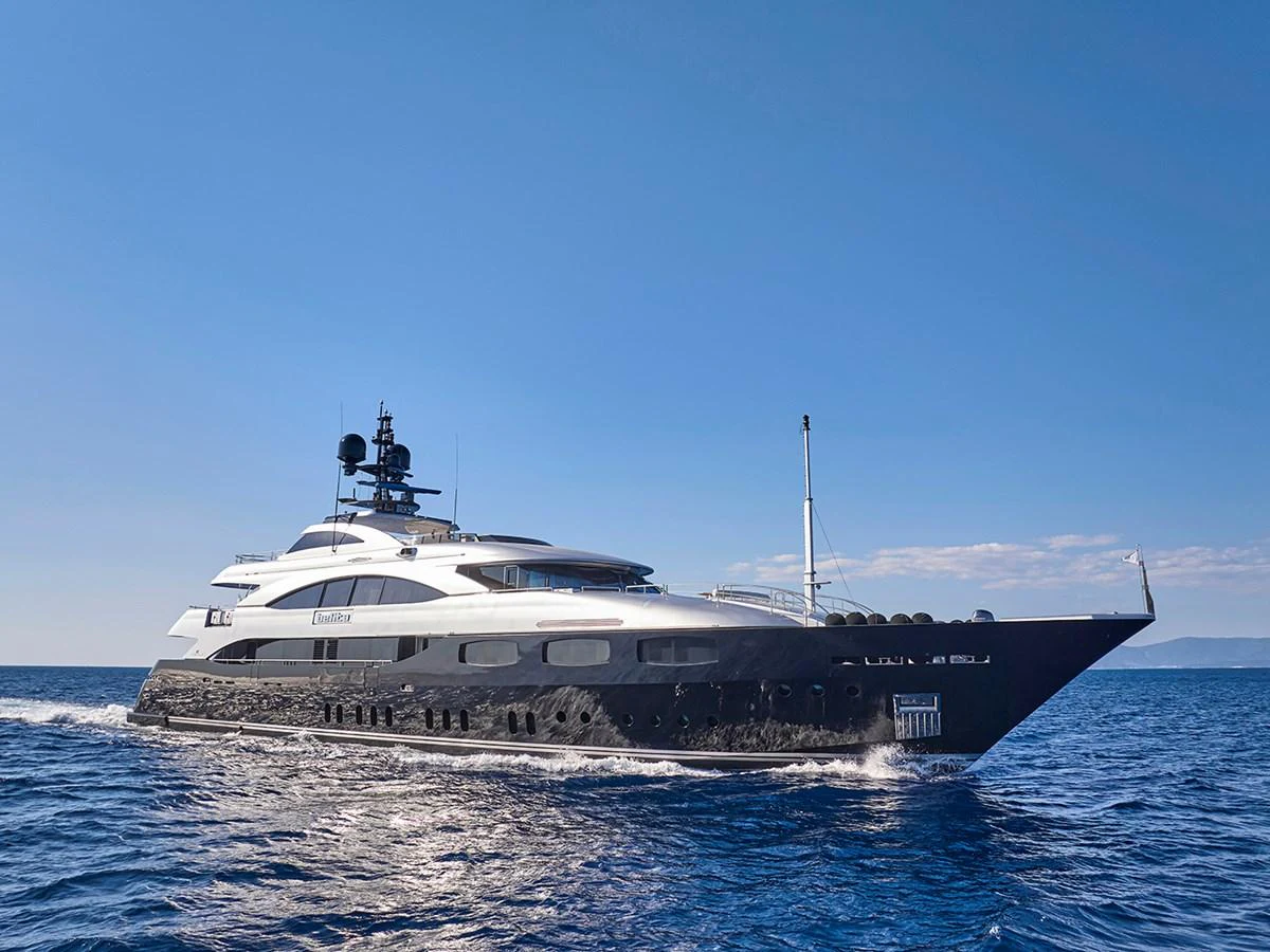 A sleek and modern yacht cruising on the open sea under a clear blue sky. aboard BELITA Yacht for Sale