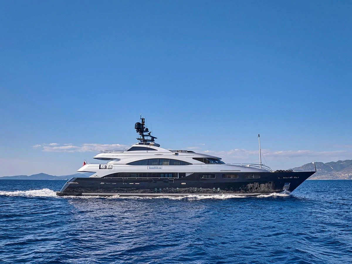 A sleek and modern yacht cruising on the open sea under a clear blue sky. aboard BELITA Yacht for Sale