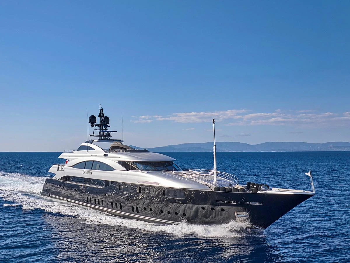 A sleek and modern yacht cruises through the open sea under a clear blue sky. aboard BELITA Yacht for Sale