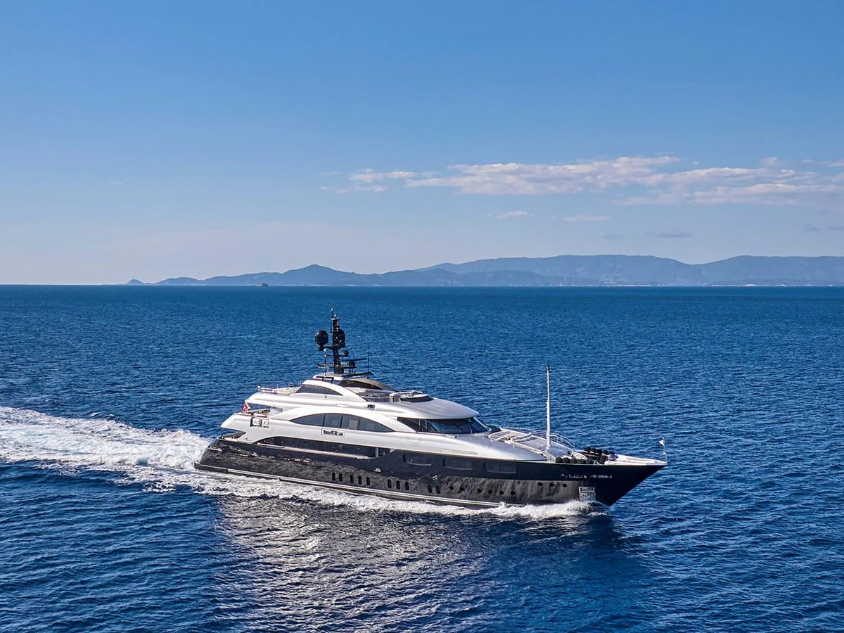 A sleek and luxurious yacht cruises through the open sea under a clear blue sky. aboard BELITA Yacht for Sale