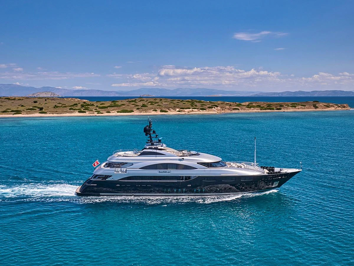A sleek and modern yacht cruises through pristine blue waters under a clear sky. aboard BELITA Yacht for Sale