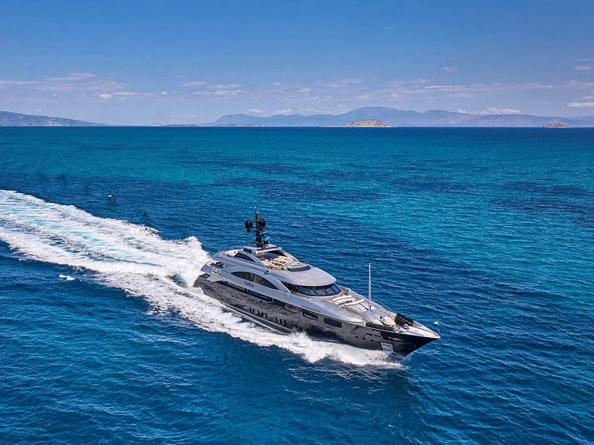 A sleek yacht cruises through clear blue waters under a bright sky. aboard BELITA Yacht for Sale