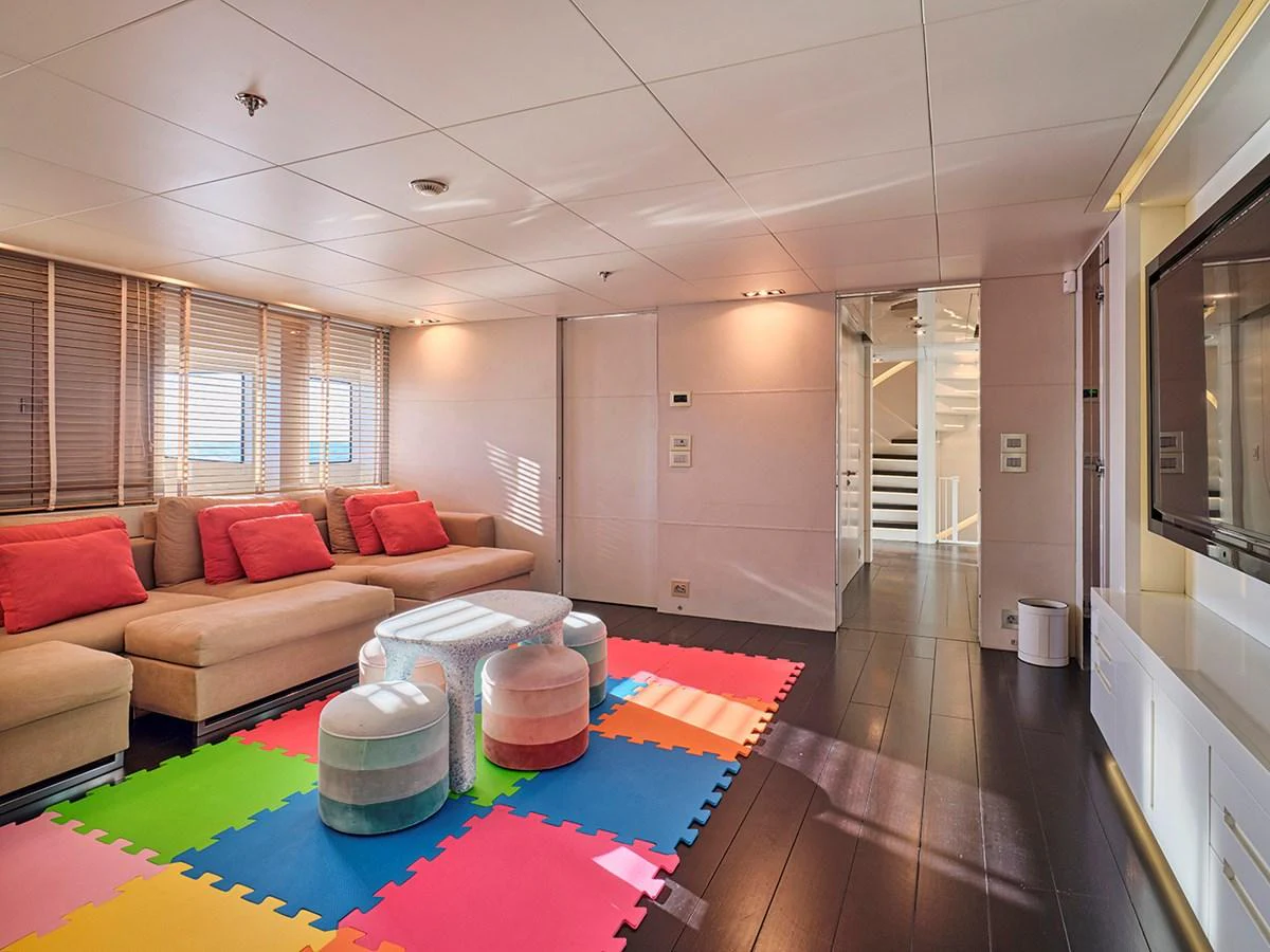 The salon features a comfortable seating area with colorful play mats and modern decor. aboard BELITA Yacht for Sale