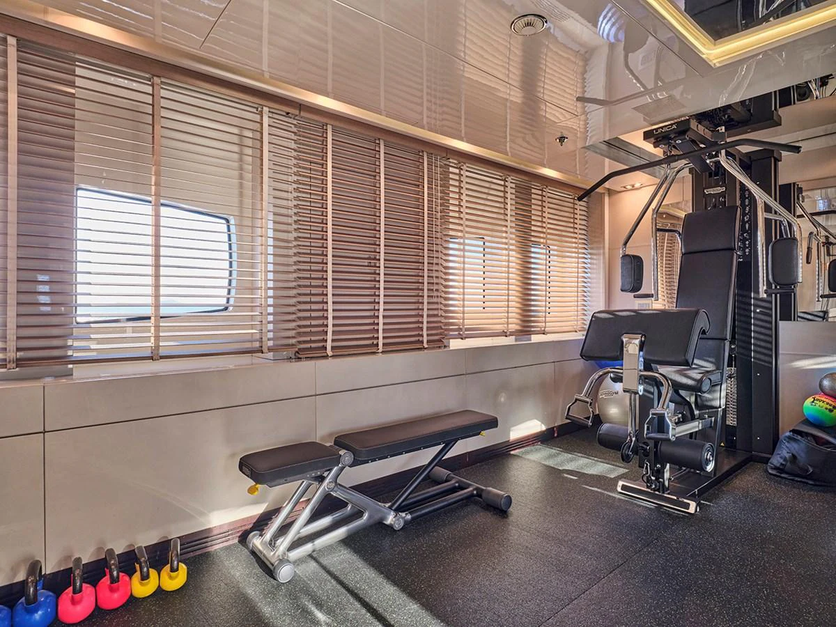 The yacht features a well-equipped gym with modern fitness equipment and ample natural light. aboard BELITA Yacht for Sale