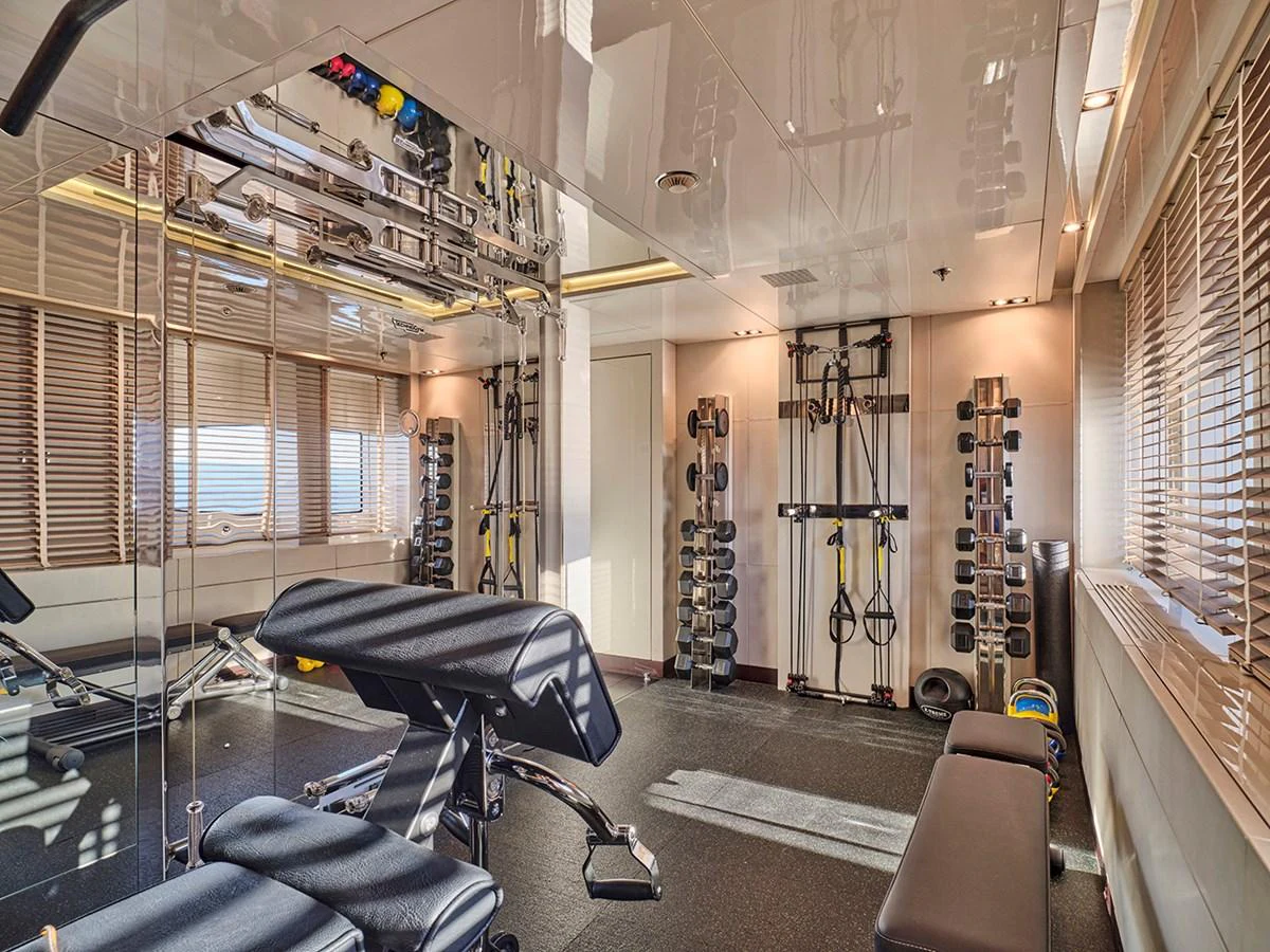 The yacht features a well-equipped gym with modern fitness equipment and ample natural light. aboard BELITA Yacht for Sale