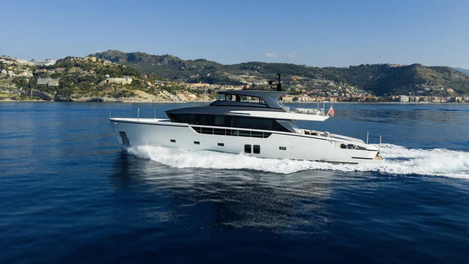 A sleek and modern yacht cruising through calm waters with a scenic coastal backdrop. aboard LA Yacht for Sale