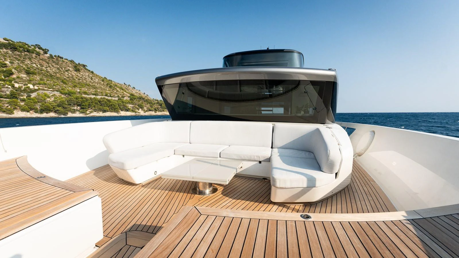 The foredeck features a spacious seating area with plush white cushions and a sleek glass table, perfect for relaxation and enjoying the view. aboard LA Yacht for Sale