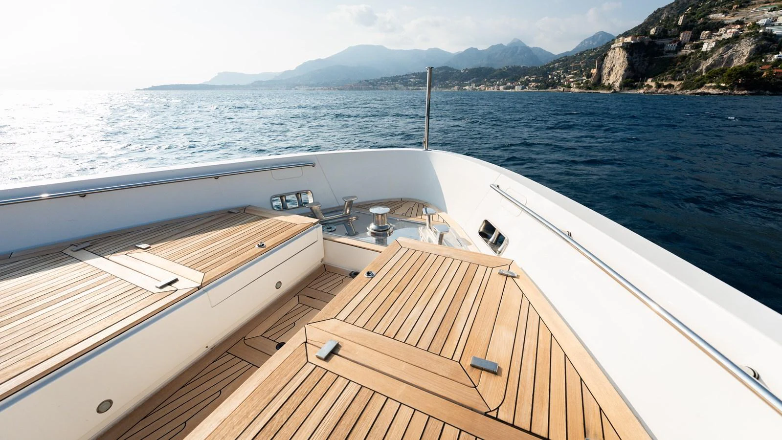 The yacht's foredeck features sleek wooden decking with stunning ocean and coastal views. aboard LA Yacht for Sale