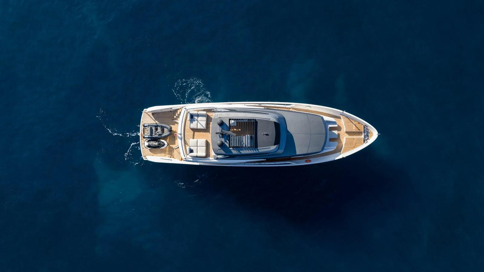 A sleek yacht cruises through deep blue waters, showcasing its elegant design from an aerial perspective. aboard LA Yacht for Sale