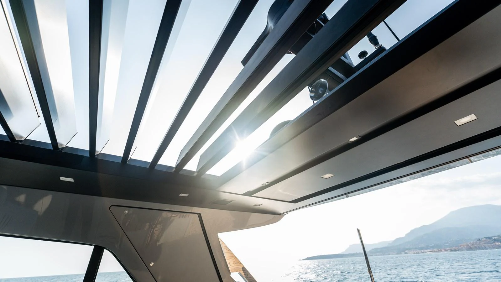 A sleek, modern yacht roof detail with a view of the sea and distant mountains. aboard LA Yacht for Sale