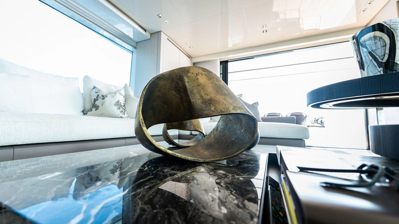 The yacht's interior features a modern and artistic decor with a stylish sculpture on a marble table. aboard LA Yacht for Sale