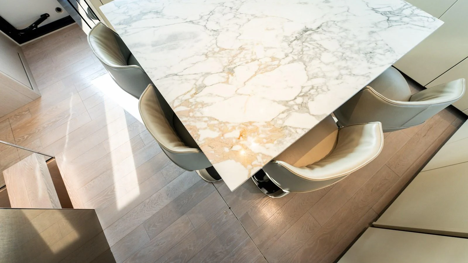The yacht features a sleek dining area with a marble table and comfortable seating. aboard LA Yacht for Sale