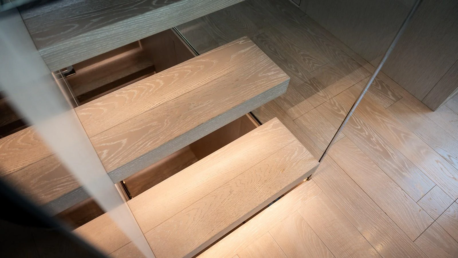 The image showcases a modern wooden staircase inside the yacht. aboard LA Yacht for Sale