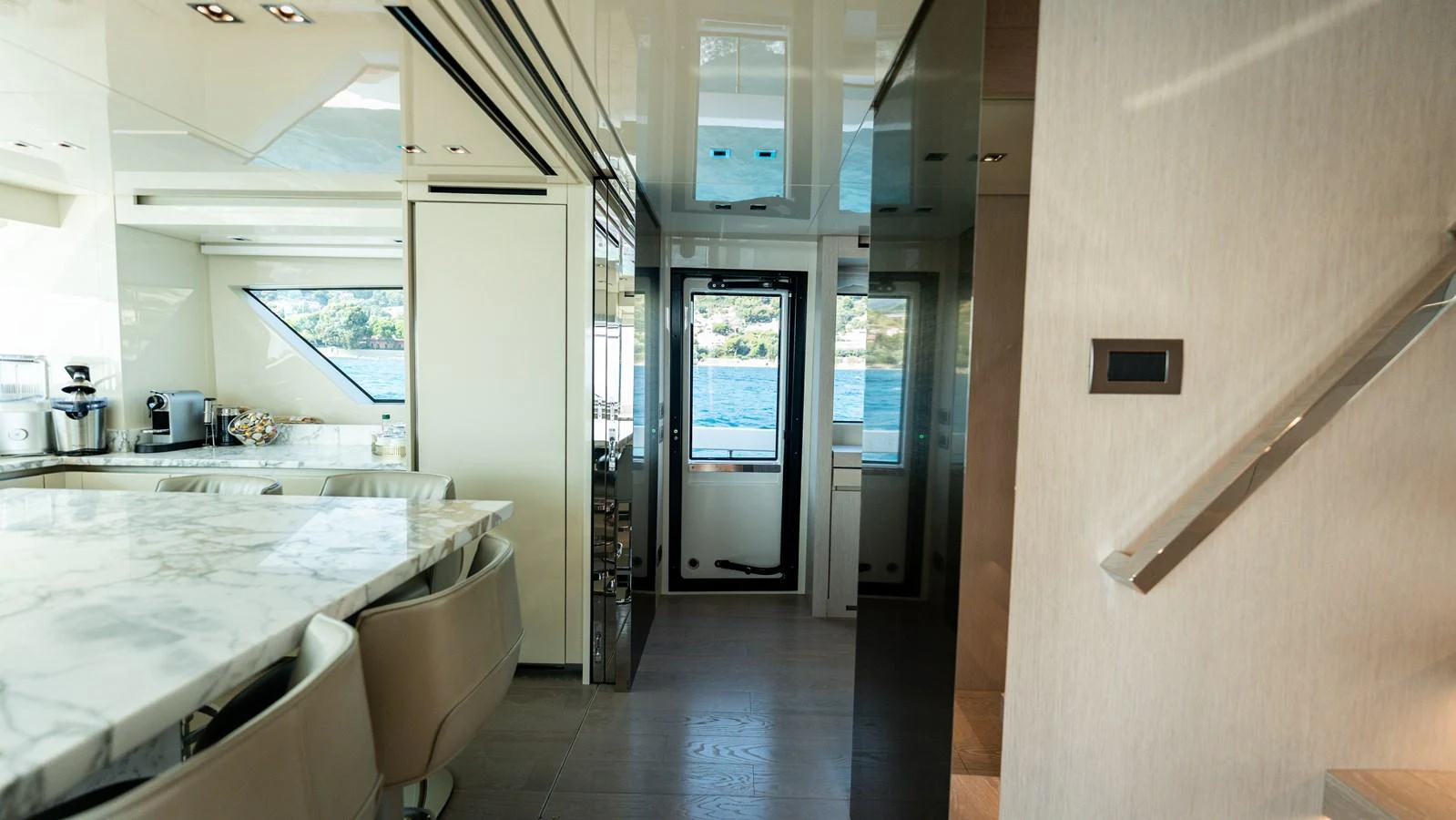 The yacht's interior features a sleek dining area with a marble table and comfortable seating, leading to a view of the water outside. aboard LA Yacht for Sale