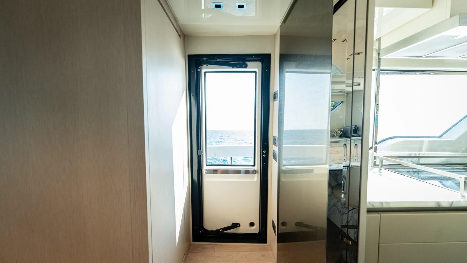 A bright interior hallway with a door leading to the exterior deck. aboard LA Yacht for Sale