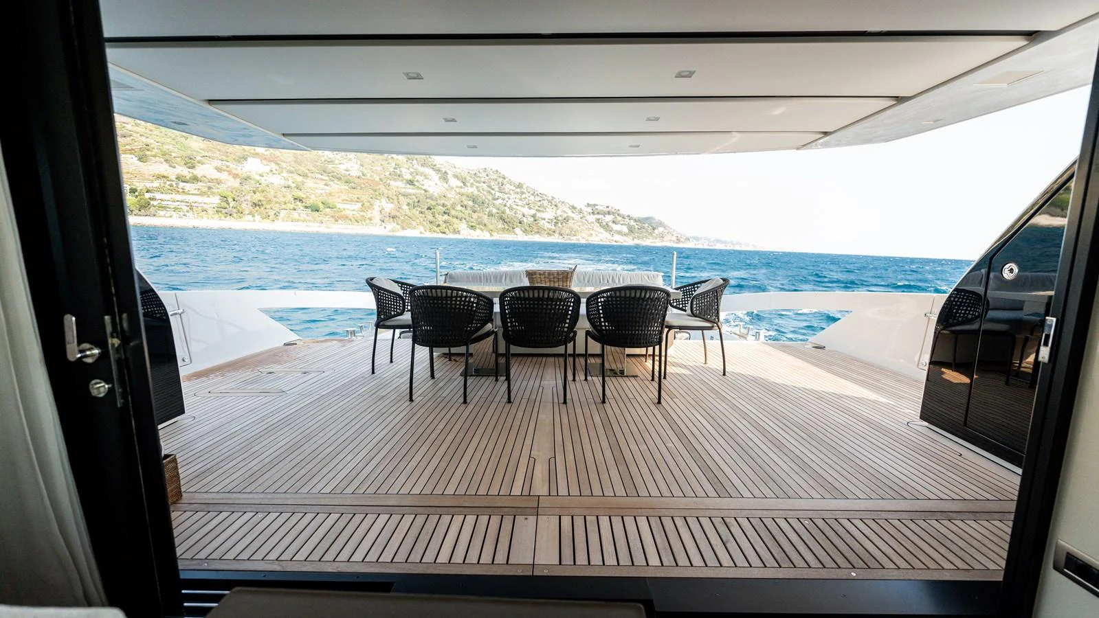 The aft deck offers a spacious and inviting area with a dining table and chairs, perfect for enjoying meals with a view of the sea. aboard LA Yacht for Sale