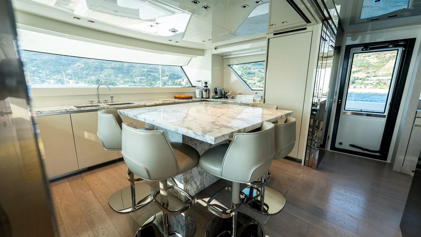 The galley features a luxurious marble island with modern seating and expansive windows offering stunning views. aboard LA Yacht for Sale