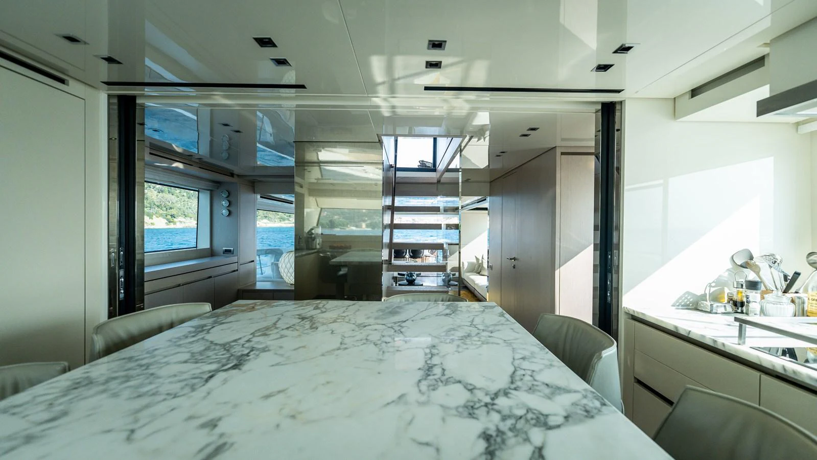 The yacht's dining area features a luxurious marble table and modern seating with a view of the water through large windows. aboard LA Yacht for Sale