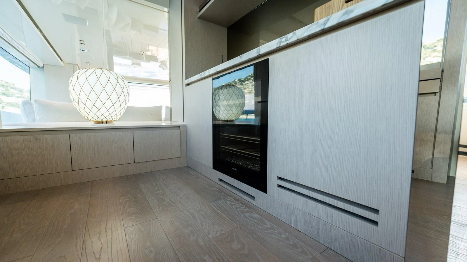 The yacht's interior features sleek cabinetry and modern design elements, highlighted by a stylish lamp and ample natural light. aboard LA Yacht for Sale