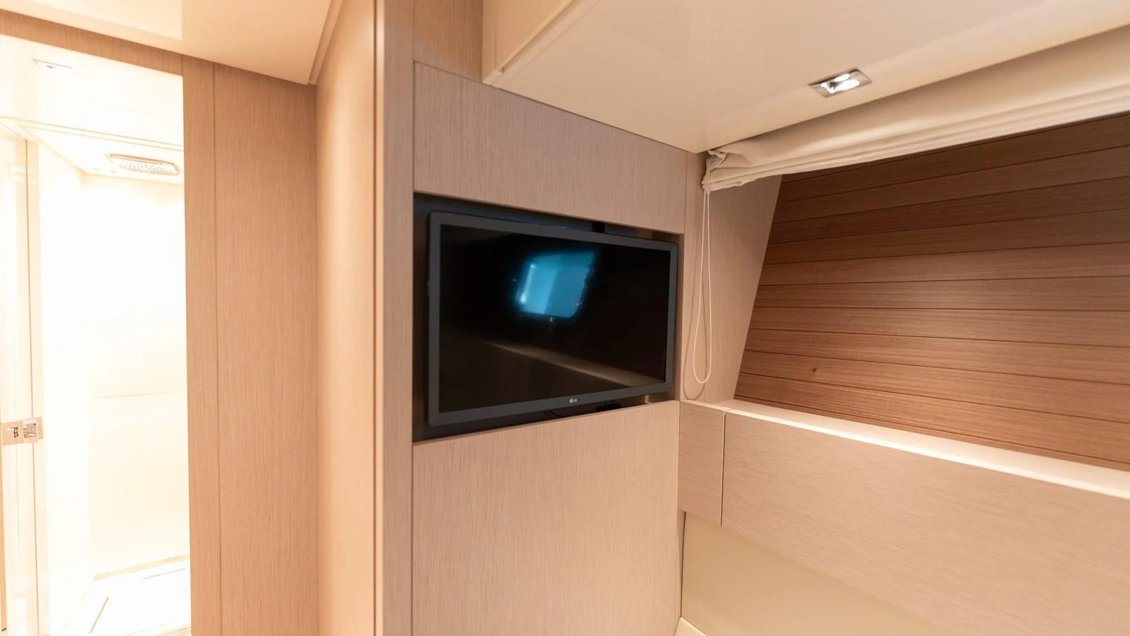 A cozy interior space featuring a mounted flat-screen television and sleek wooden paneling. aboard LA Yacht for Sale