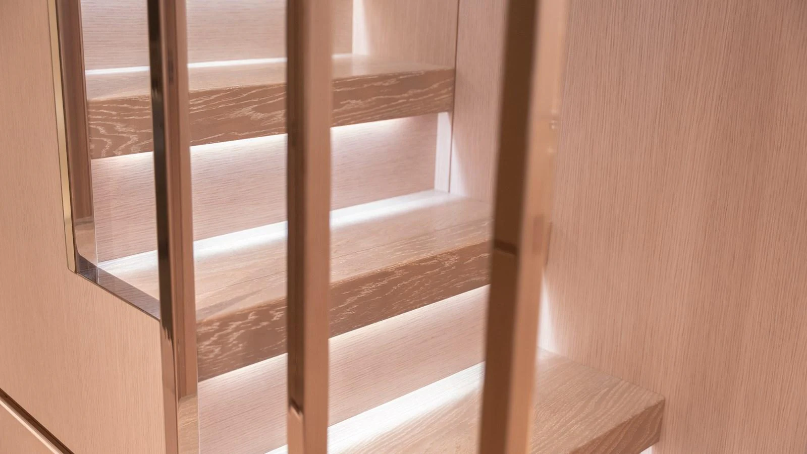 A modern staircase with sleek wooden steps and ambient lighting. aboard LA Yacht for Sale