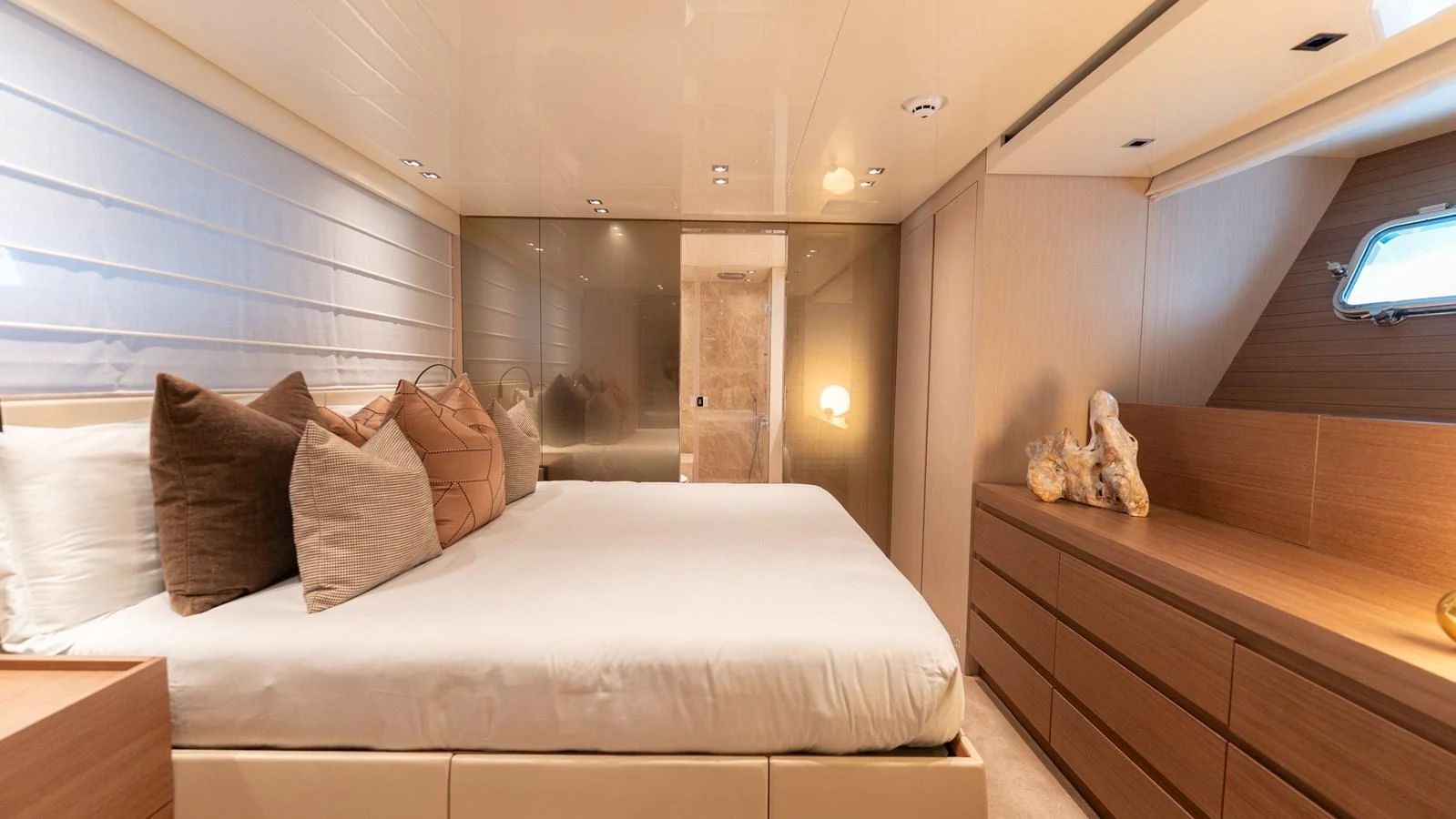 The stateroom features a luxurious bed with plush pillows and elegant wooden cabinetry. aboard LA Yacht for Sale