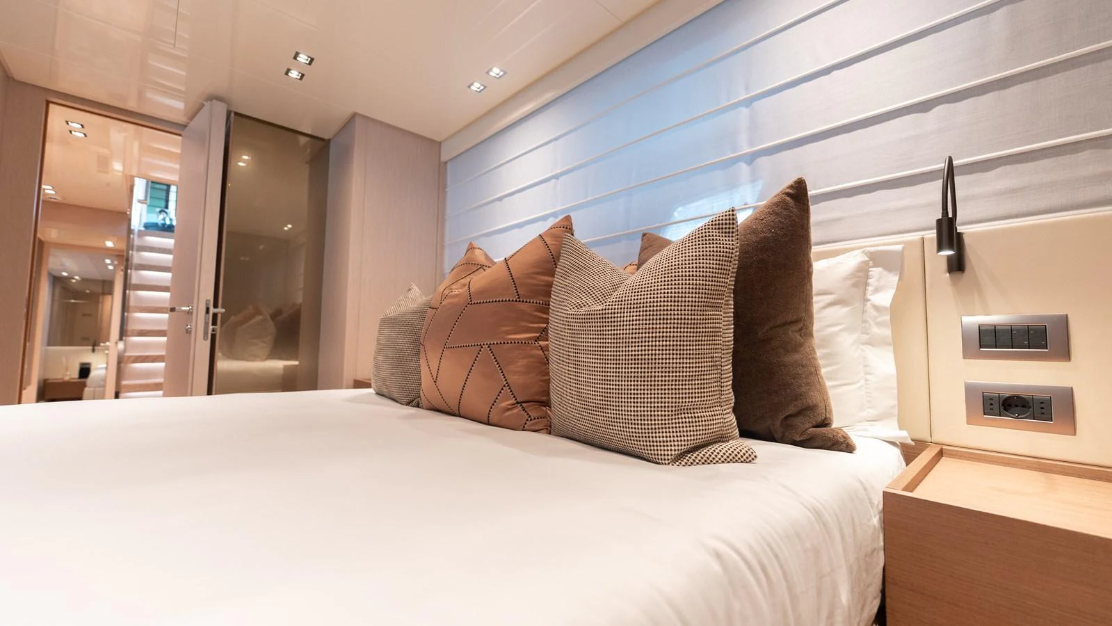 The stateroom features a plush bed with elegant pillows and modern lighting. aboard LA Yacht for Sale