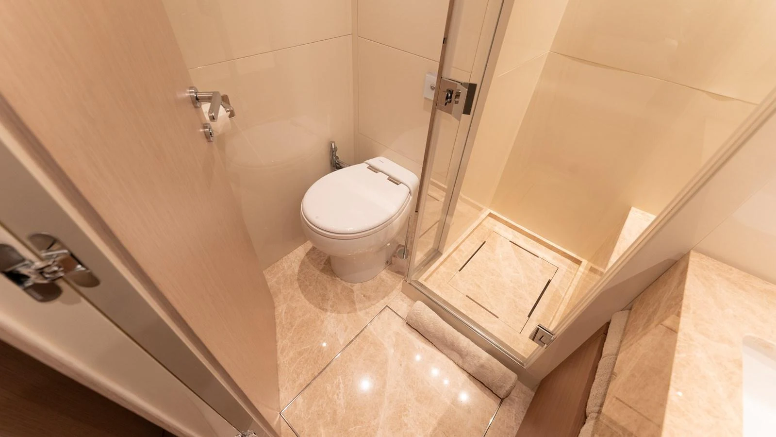 A pristine yacht bathroom featuring a modern toilet and a glass-enclosed shower. aboard LA Yacht for Sale