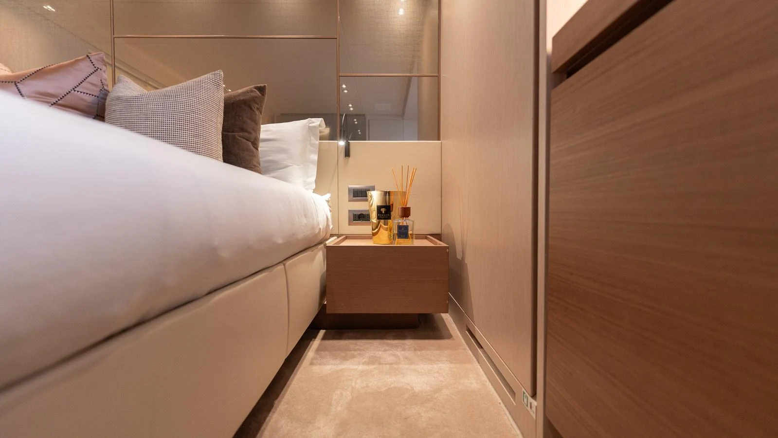 The stateroom features a luxurious bed with plush pillows and a sleek bedside table. aboard LA Yacht for Sale